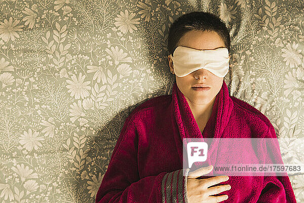 Frau mit Augenmaske entspannt sich zu Hause im Bett
