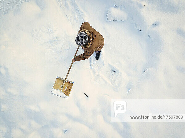 Man cleaning snow with snow shovel in winter