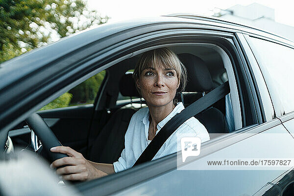 Thoughtful woman driving car on road trip