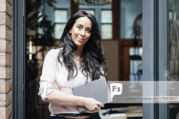 Businesswoman with tablet PC standing at entrance of office building