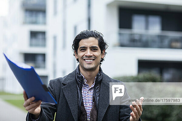 Happy man in warm clothing holding blue file