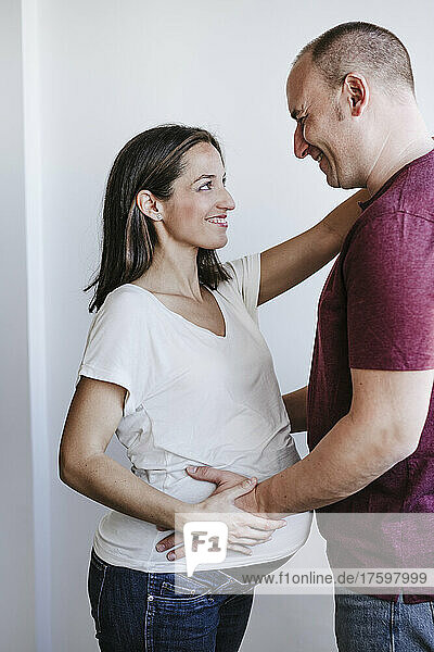 Happy man looking at pregnant woman at home