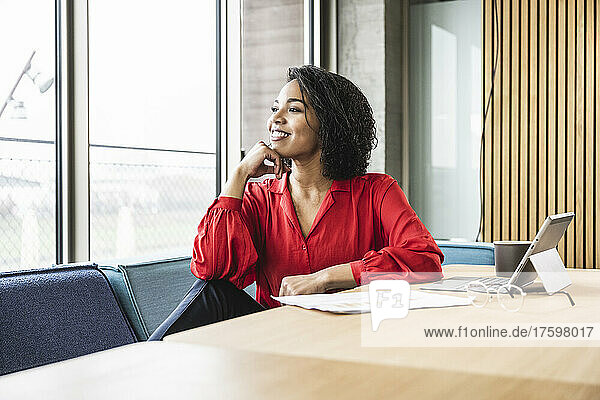 Thoughtful businesswoman looking through window at work place