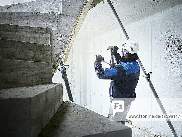 Worker removing pipes from concrete stairs at construction site