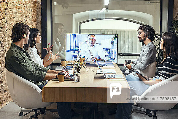 Businesswoman explaining businessman on video call in meeting at creative office