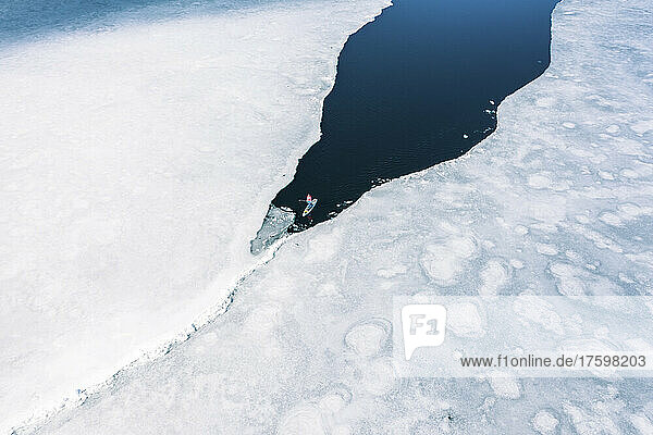 Germany  Bavaria  Aerial view of lone man paddleboarding between ice floes in Eibsee lake