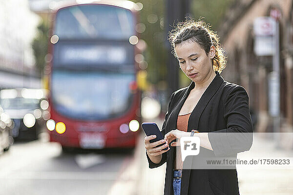 Young commuter with smart phone checking time on street
