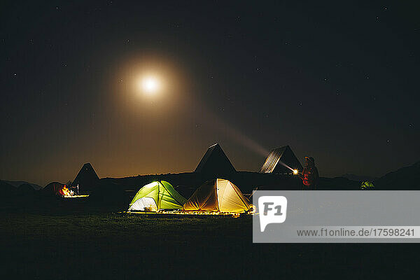 Tourist with flashlight standing near illuminated tents at Caucasian State Nature Reserve in Sochi  Russia
