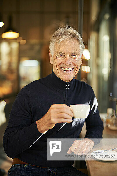 Smiling senior man having coffee in cafe