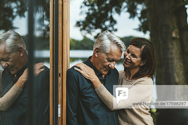Smiling woman looking at senior man standing by glass wall