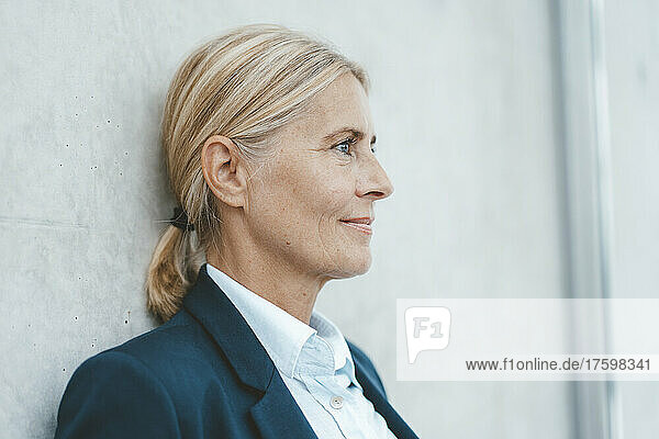 Blond businesswoman leaning on wall