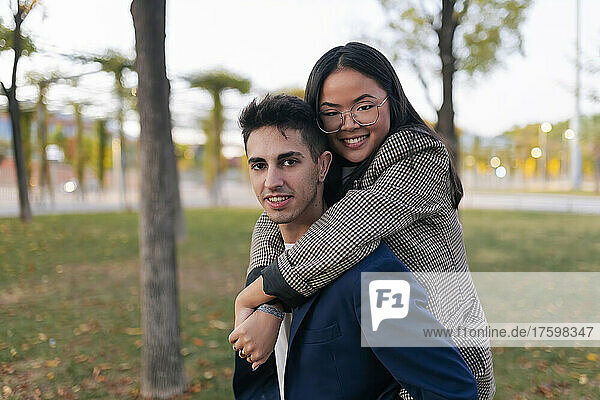 Businessman piggybacking colleague at public park