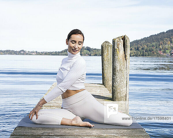 Beautiful woman practicing yoga on jetty