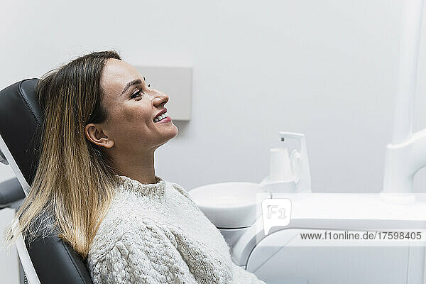 Happy woman on dentist chair in operating room at clinic