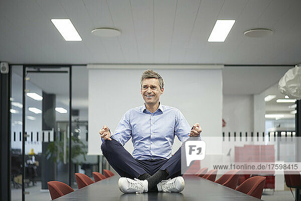 Smiling businessman meditating in meeting room at office