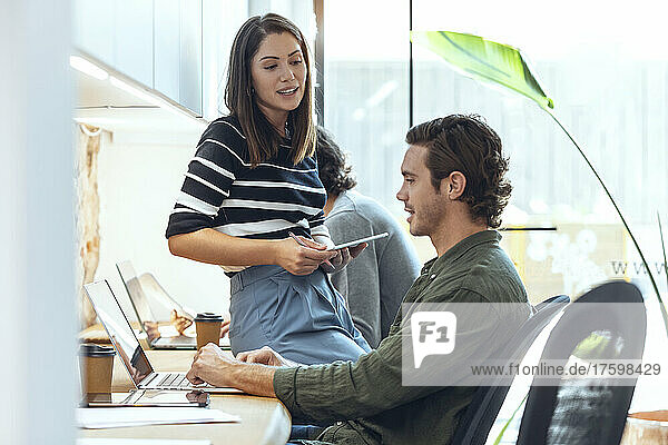 Businessman and businesswoman discussing while working in coworking office