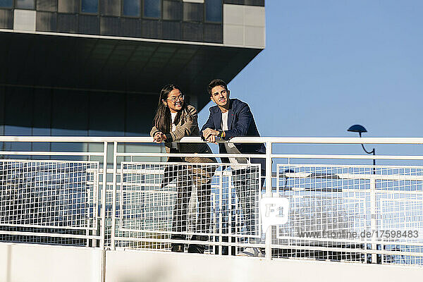Young business colleagues leaning together on railing