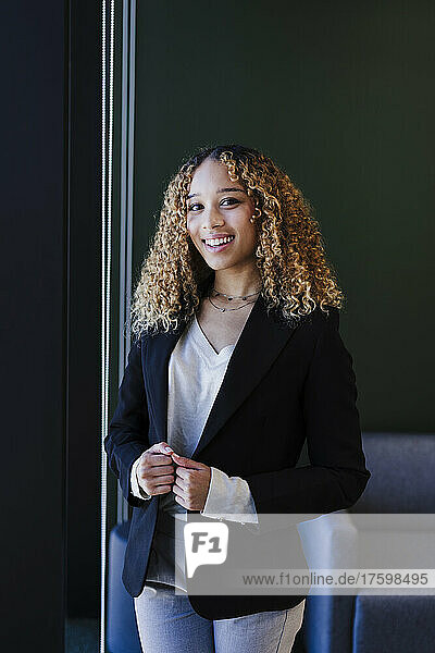 Smiling businesswoman holding blazer in office