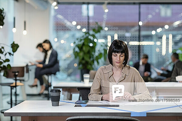 Businesswoman texting on smart phone in office