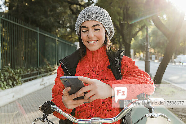 Happy woman with bicycle using mobile phone