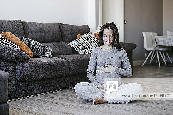 Pregnant woman sitting cross-legged at home