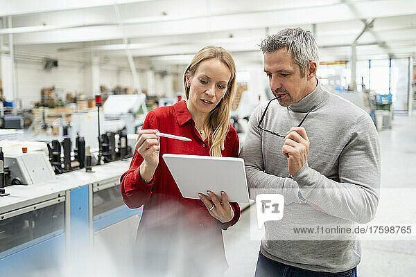 Blond businesswoman discussing over tablet PC with businesswoman in industry