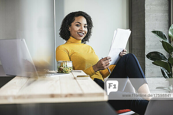 Young businesswoman with paper document at work place