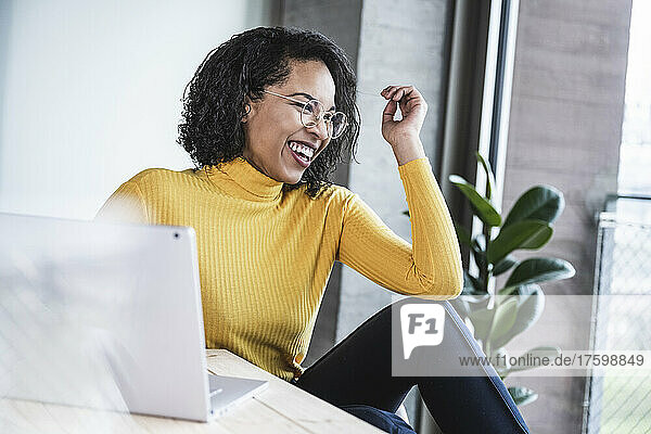 Businesswoman laughing by laptop at desk in office
