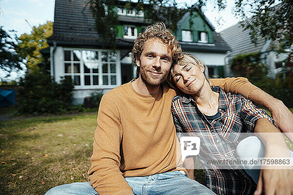 Woman leaning with eyes closed on man in garden