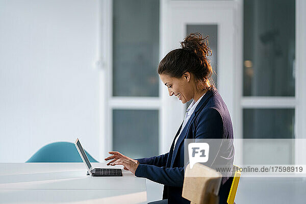 Smiling businesswoman using tablet PC at desk