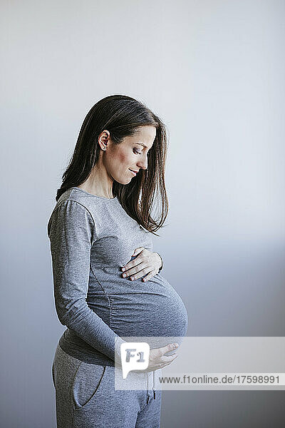 Schwangere Frau steht vor der Wand