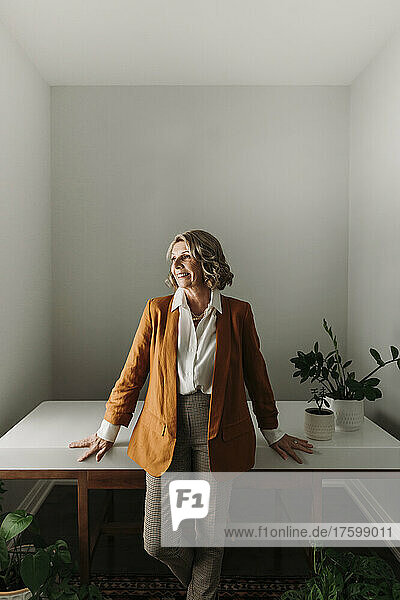 Smiling senior businesswoman standing by desk at home