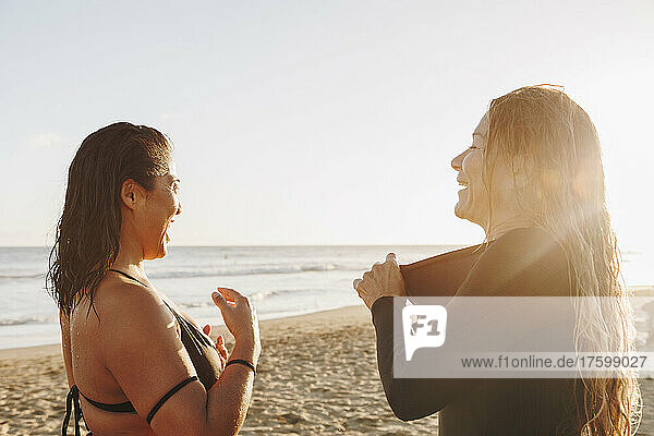 Happy women taking off wetsuit after surfing at beach on sunset  Gran Canaria  Canary Islands
