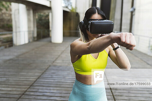 Sportlerin mit VR-Brille boxt auf Fußweg