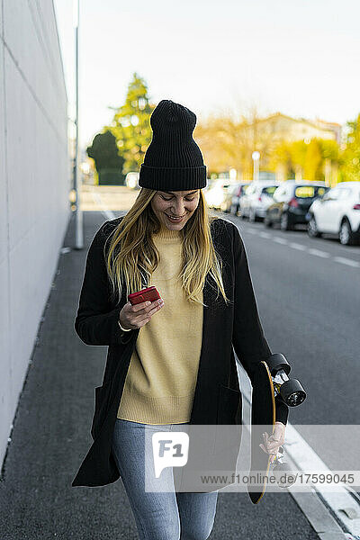 Young woman with mobile phone walking on footpath