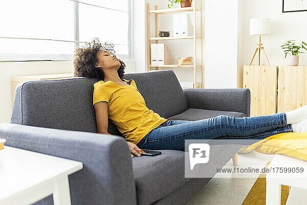 Young woman sleeping on sofa in living room at home