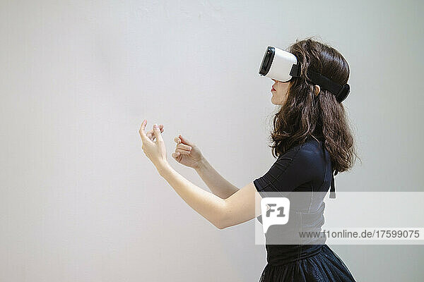 Young woman with VR glasses gesturing in studio
