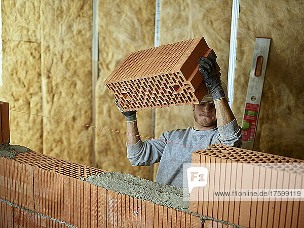 Bricklayer holding slab of brick working at construction site