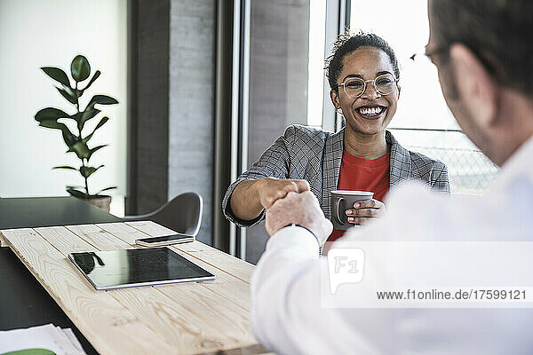 Happy businesswoman doing fist bump with colleague in office
