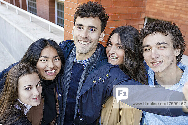 Lächelnde  gemischtrassige Freunde  die ein Selfie auf dem Universitätscampus machen
