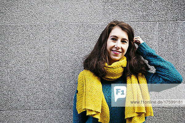 Smiling woman with scarf in front of wall
