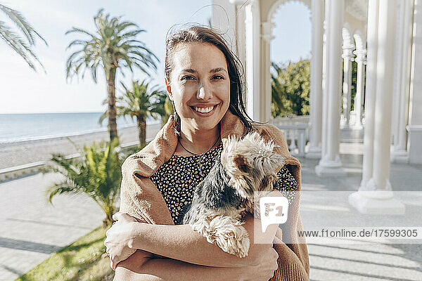 Smiling young woman with dog at beach