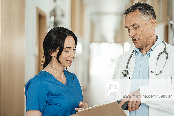Nurse and doctor discussing over medical record in hospital