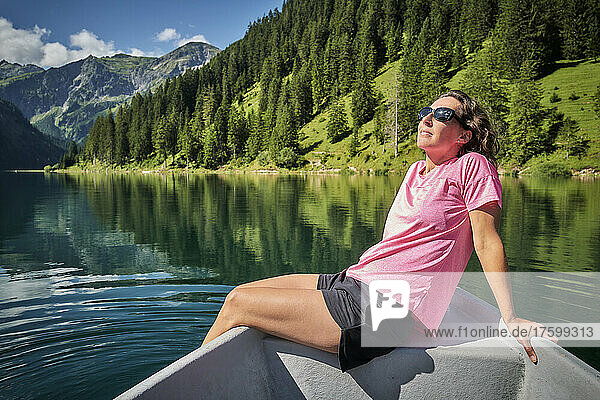 Woman sitting on rowboat dipping feet in water
