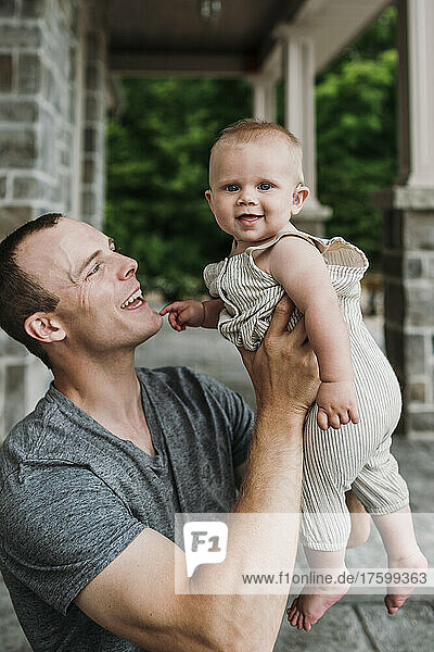 Happy father lifting cute baby son at porch