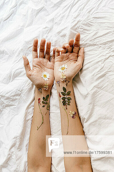 Woman's hands with flowers and twigs on bed