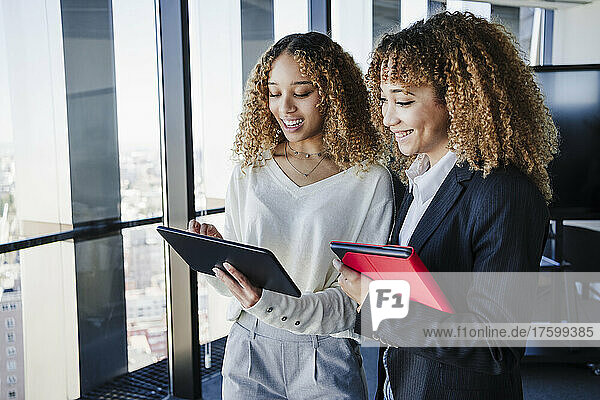 Businesswomen sharing tablet PC working in office