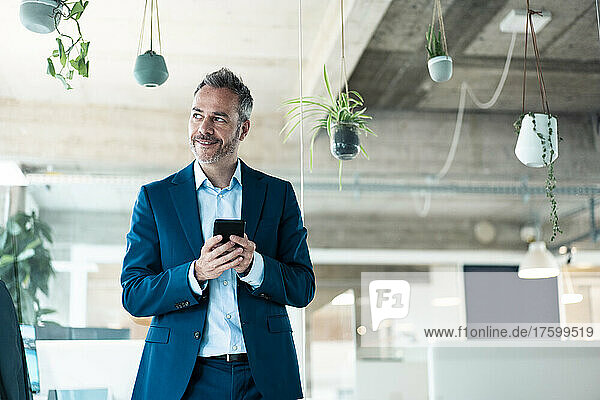 Smiling businessman using mobile phone at workplace