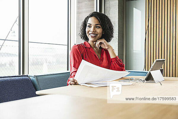Smiling businesswoman with documents at work place