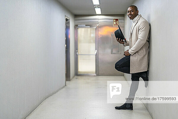 Mann mit Hut steht auf einem Bein und lehnt an der Wand an der U-Bahn-Station